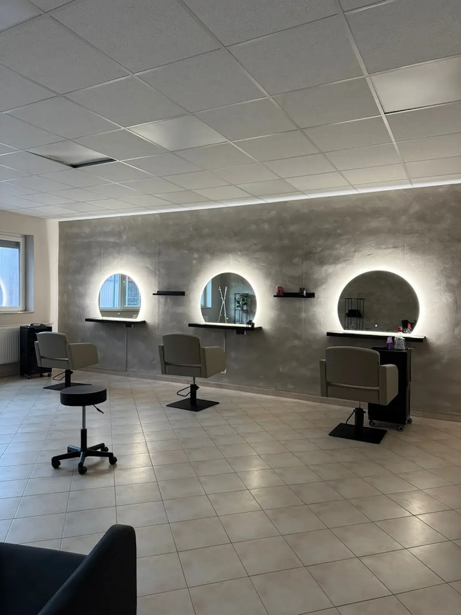 Drei runde, hinterleuchtete Spiegel an der Kalkputzwand des Salons